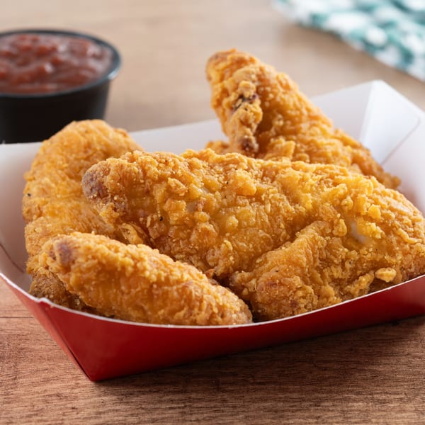 Crispy fried chicken tenders in a red and white paper tray with a side of salsa.