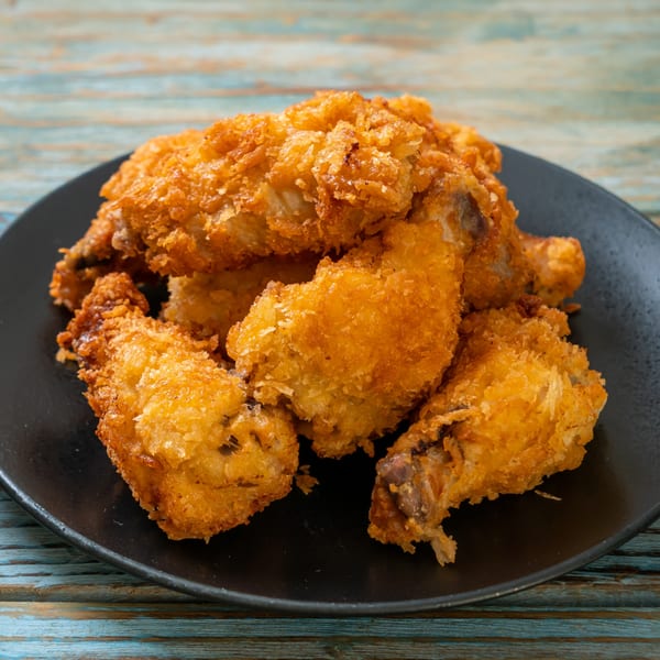 Crispy, golden-brown fried chicken pieces from Hip Hop Fish & Chicken, piled on a black plate.